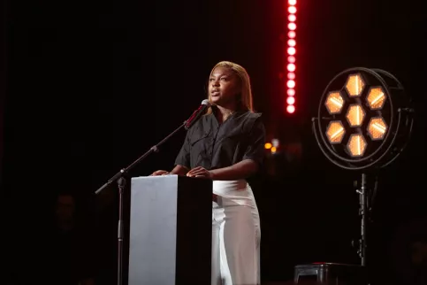 Jeune femme sur scène derrière un pupitre avec micro